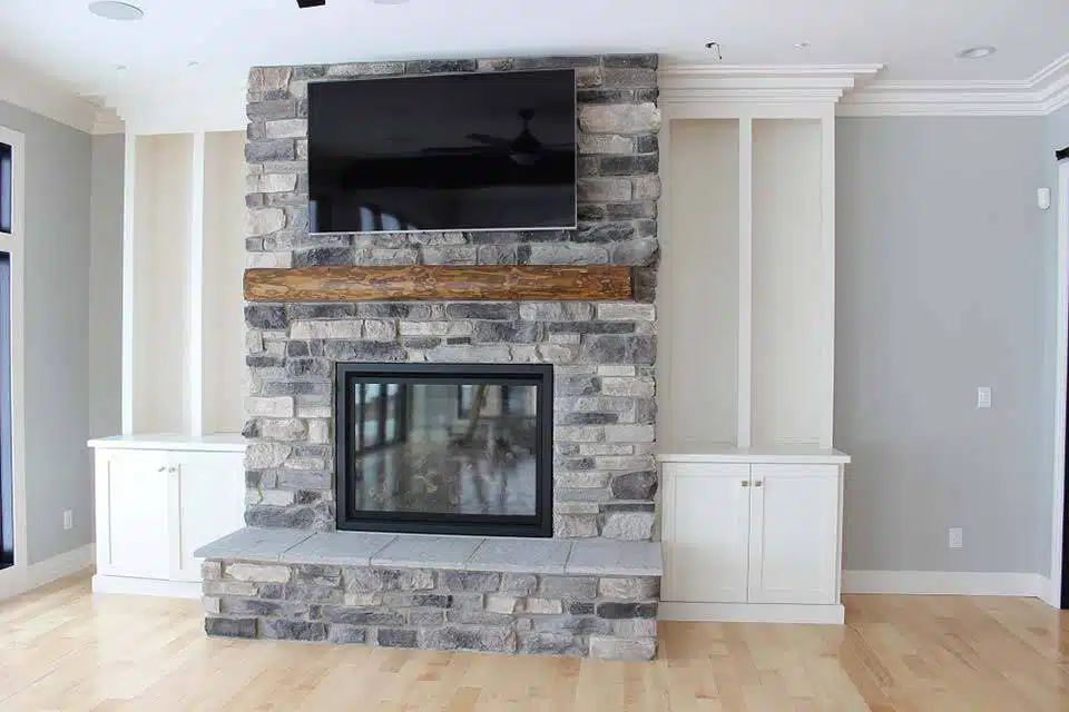 Gray stone fireplace with white built-ins on either side in custom-built Winona Lake home.