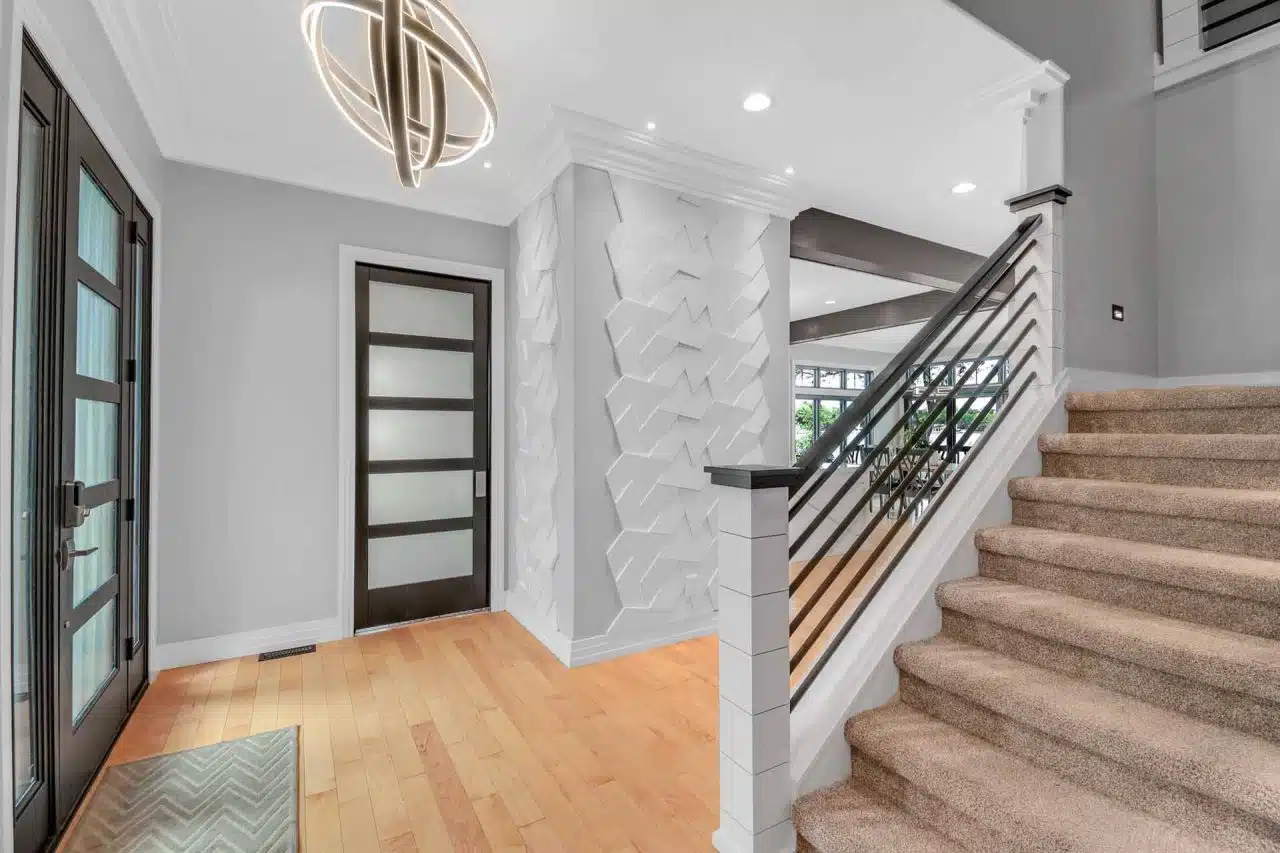 Interior entrance and staircase of Winona Lake two-story custom-built home with white siding and black trim.