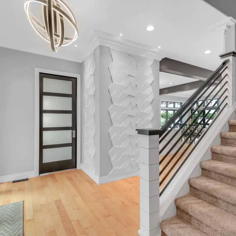 Interior entrance and staircase of Winona Lake two-story custom-built home with white siding and black trim.