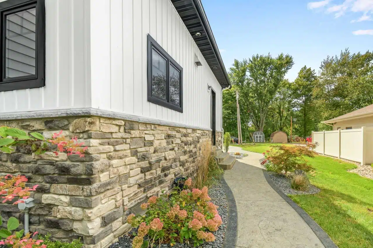 Exterior of custom-built home with white siding and natural stone.