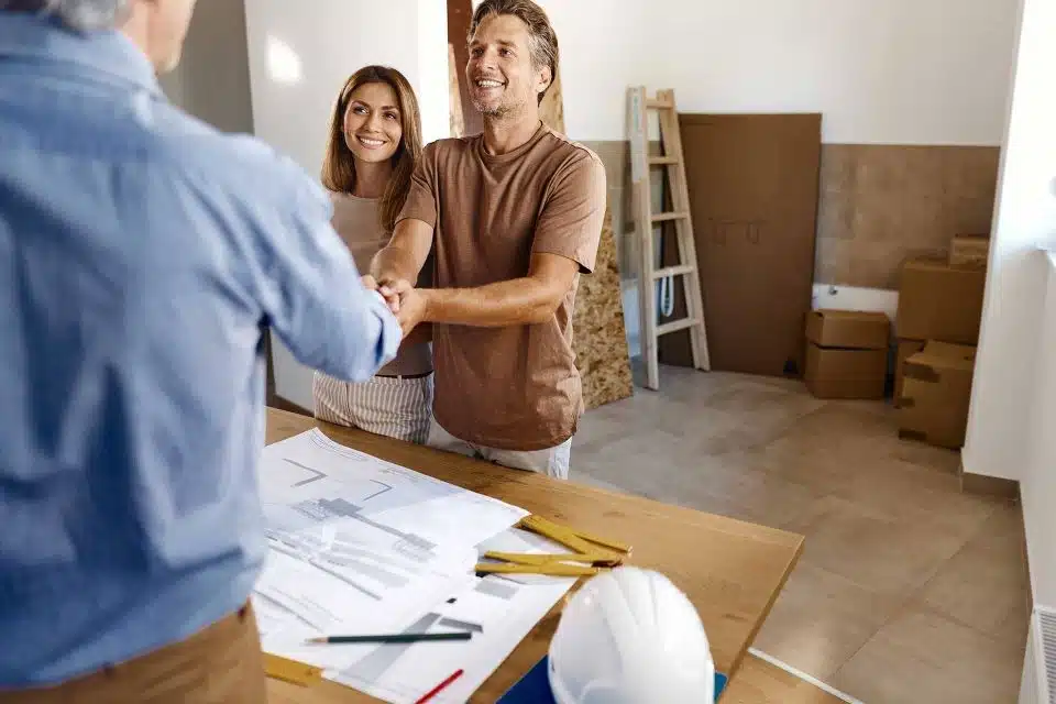 Man shaking a contractor's hand while woman stands next to him smiling.